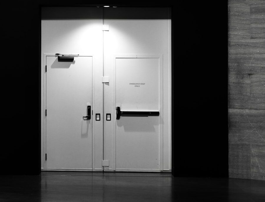 Two white doors with black handles in dark hallway.